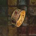 Gold bracelet with gemstones on a textured surface