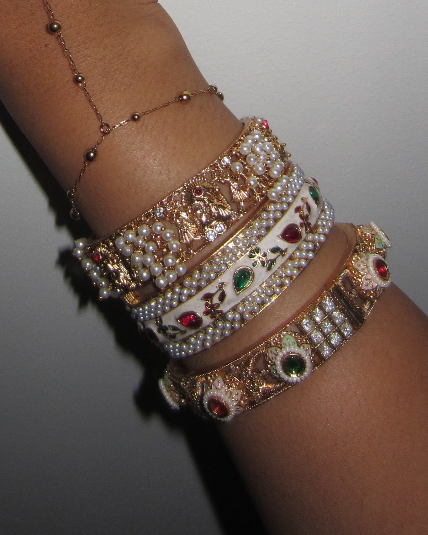 Hand wearing multiple bangles on a plain background
