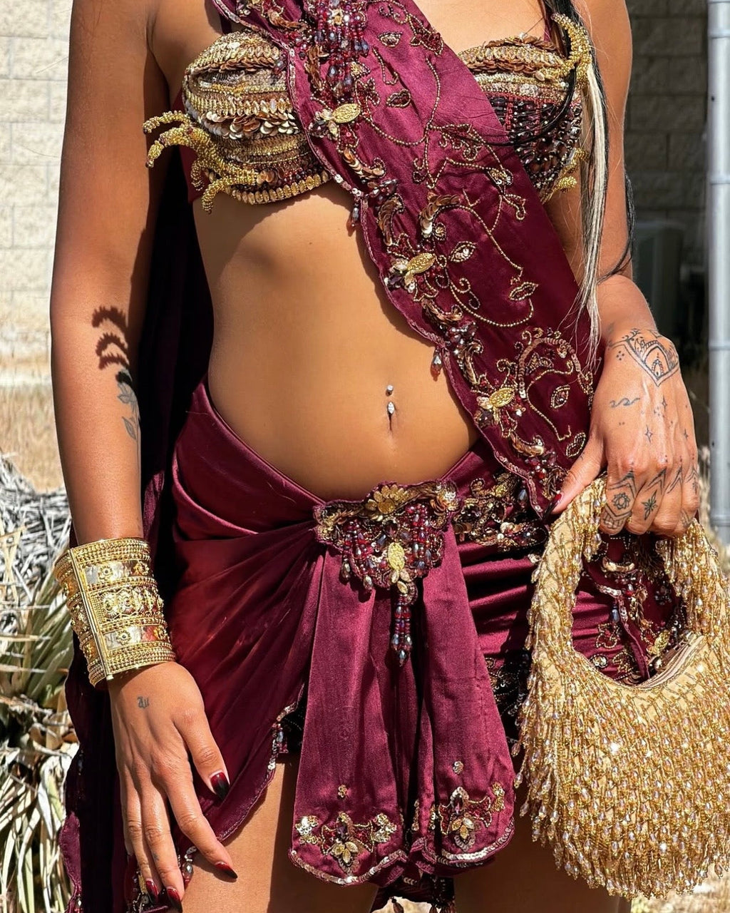 Person wearing a detailed maroon outfit with gold accents and accessories.