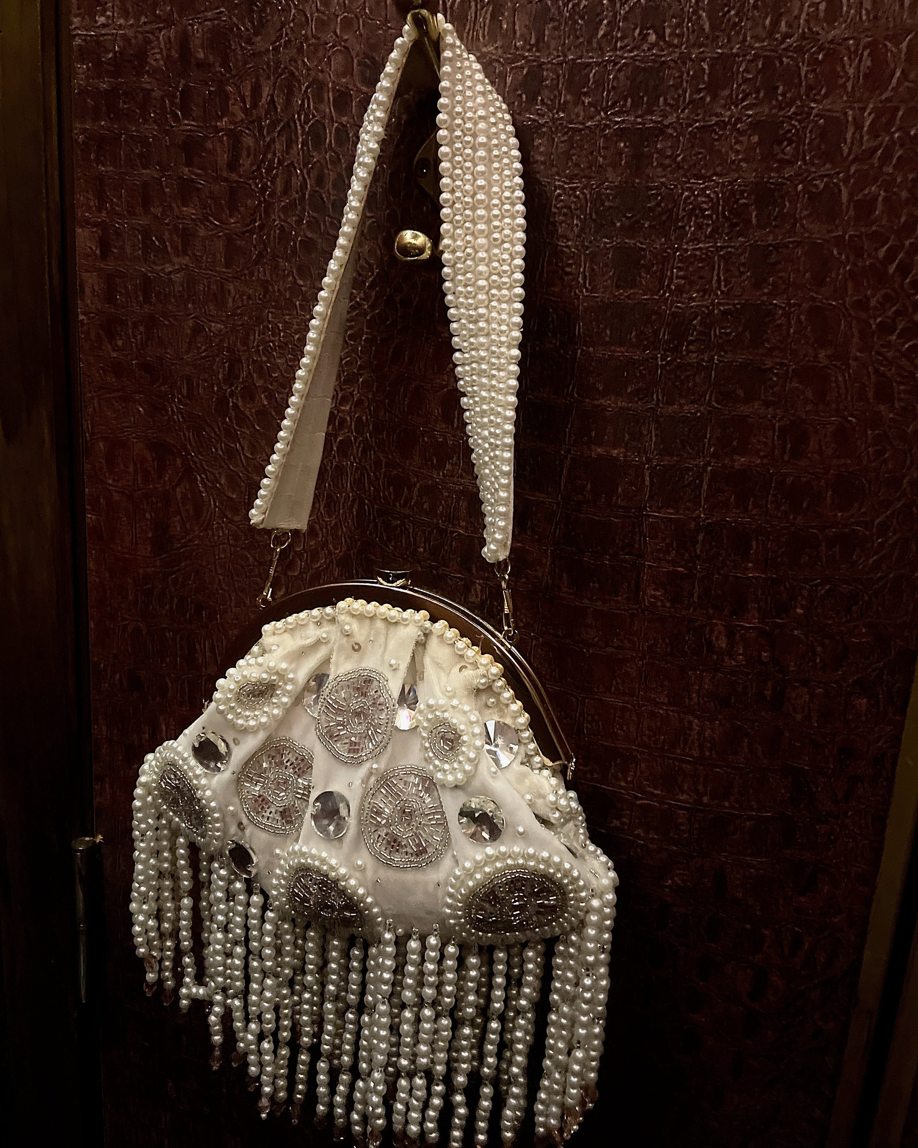 Decorative handbag with pearl embellishments on a textured brown background