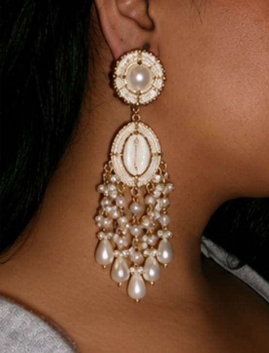 A close-up of a model's ear wearing a large, ornate gold and pearl drop earring with multiple cascading pearl beads.